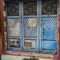 Weathered Blue Entrance Door With Decorative Patterns Striped Panels Bronze Plates And Red Frame