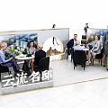 Modern Exhibition Booth Tables and Chairs with People Interacting and Display Backdrops