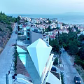 Modern Geometric Single Family Villa With White Roof Large Windows And Hillside Rocky Landscape