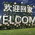 Welcome Home Sign Decorated With Green Plants And Pink Flowers