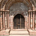 Romanesque Entrance Gate With Red Brick Structure Carved Archway Stone Columns And Wooden Doors