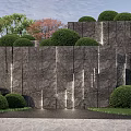 Natural Textured Stone Wall Landscaped With Trimmed Bushes And Green Trees