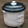 Oster Electric Rice Cooker With White Body And Black Lid On Kitchen Countertop