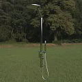 Silver Shower Head Standing On Green Grass With Wooded Background In Outdoor Scene