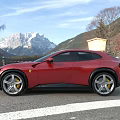 Red Sports Car Parked Outdoor With Mountain View Building And Flag