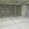 Interior View Of Room With Metal Bars Concrete Walls And Gray Door
