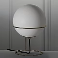 White Spherical Lampshade Table Lamp with Golden Circular Metal Frame and Gray Striped Wall