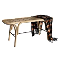 Light Wooden Footstool With Curved Frame Wicker Top And Draped Plaid Blanket