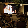Outdoor Restaurant With Large Screen Outdoor Seating Plants And Wooden Tables