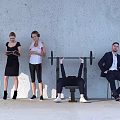Group of People With Various Activities Including Barbell Lifting Standing And Sitting Against Gray Wall
