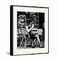 Vintage Black and White Woman Portrait Painting Seated in Wicker Chair at Outdoor Café