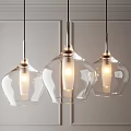 Three Modern Transparent Glass Pendant Lights With Metallic Accents Illuminated In Interior