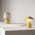 Two Minimalist Table Lamps With Beige And Yellow Shades Yellow Bases On White Display Stands