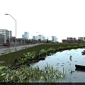 Modern Industrial Factory Building Featuring Pond Street Lights Greenery And City Skyline Under Clear Sky