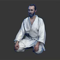 Man In White Judo Uniform Sitting Cross Legged On Dark Background With Beard