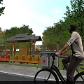 Entrance Gate Area With Roofed Pavilion Red Yellow Benches Trees And Bicycle Rider