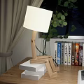 Wooden Table Lamp On Stacked Books With Green Plant Bookshelf And Curtain