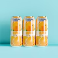 Three Cans of Orange Juice Drink with Orange Slices Design on Light Blue Background