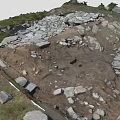 Ancient Archeological Site With Scattered Stones Excavated Earth And Grassy Edges