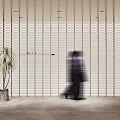 Modern White Vertical Slat Partition In Interior Space With Plant And Walking Person