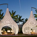 White Conical Woven Tents With Outdoor Seating Among Palm Trees And Mountain Backdrop