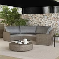 Outdoor Wicker Sofa With Gray Cushions Round Coffee Table And Green Plants By Stone Wall
