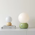 Modern Minimalist Table Lamps with Spherical White Shades and Green Yellow Bases on Books