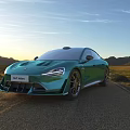 Green Sports Car Front View on Open Road with Mountain Landscape and Sunset Sky