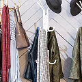 Stylish Clothes Hangers With Hanging Clothes Bags And Hats Against Geometric Patterned Wall