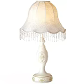 White Table Lamp with Decorative Pattern on Base and Elegant Lace Lampshade Adorned with Fringes