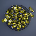 Golden And Blue Wrapped Candies In Transparent Glass Bowl With Scattered Pieces