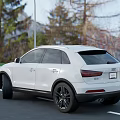White Audi SUV Parked On Road With Mountains Trees And Red Flowers