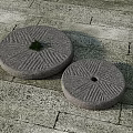 Two Traditional Stone Millstones on Textured Stone Pavement with Small Green Plant