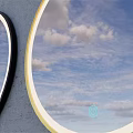 Two Decorative Wall Mirrors With Black And Yellow Frames Reflecting Blue Sky And White Clouds