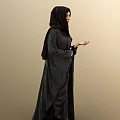 Woman Wearing Black Abaya And Hijab Standing Against Beige Background With Hand Gesture