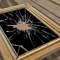 Broken Mirror with Golden Frame and Cracked Glass on Wooden Floor