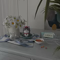 Decorative Ornament Collection with White Daisies Cat Figurine Blue Bowl Notebook and Striped Cloth on Table