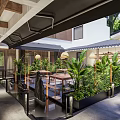 Modern Restaurant Outdoor Courtyard With Green Plants Water Feature And Wooden Tables