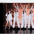 Five Women In White Outfits Singing On Stage With Microphones And Stage Lights