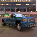 Blue GMC Truck Parked On City Street With High Rise Buildings And Night Lights