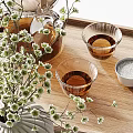 Glass Teapot and Small Teacups with Ceramic Vase and Flowering Branches on Wooden Tray