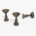 Three Bronze Candlesticks Displayed On White Background With Two Standing And One Overturned