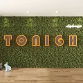 Greenery Wall Design Featuring Orange TONIGH Letters And Lavazza Logo On Wooden Floor With Small Animal Decorations