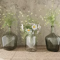 Glass Vases With White Daisies And Green Tiny Flowers On Wooden Table Against Weathered Wall