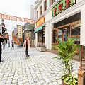 Traditional Chinese Commercial Street With Cobblestone Pavement Shop Signs And Pedestrians