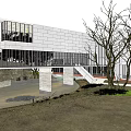 Modern Cultural Center Building With Large Glass Windows And Water Pool Reflection In Natural Surroundings