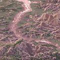 Aerial View Canyon Landscape With Winding River And Rolling Hills Covered In Green Vegetation