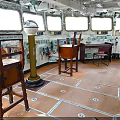 Ship Wheelhouse Interior With Wooden Chairs Tables Control Panels And Orange Floor