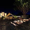 Outdoor Patio Night View With Wooden Tables Chairs Green Trees And String Lights