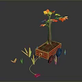 Tree with Yellow and Red Leaves in Red Cart Surrounded by Green Grass